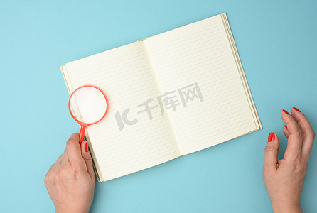 蓝色背景上带空白白纸和红色放大镜的纸质笔记本