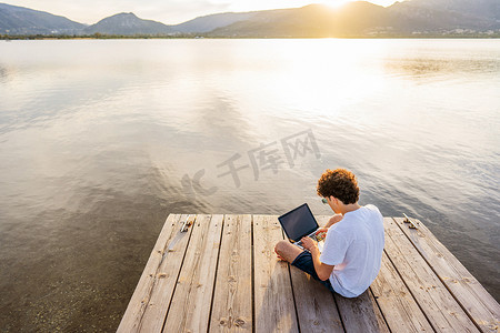 书呆子在日落时花时间在户外编程，使用笔记本电脑编写代码。