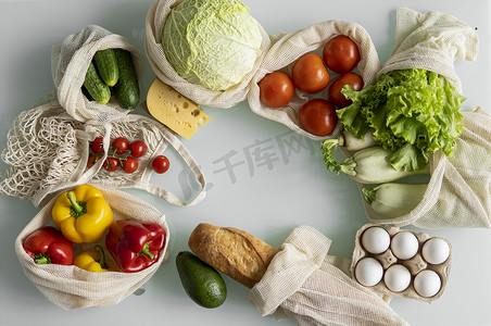 把卡摄影照片_女人的手，拿着一个可重复使用的食品袋，在家里的厨房里放着蔬菜，把卷心菜拿出来。