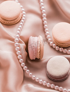 丝绸背景上的甜马卡龙和珍珠首饰、巴黎别致的珠宝、法式甜点食品和豪华糖果品牌的蛋糕马卡龙、节日礼物