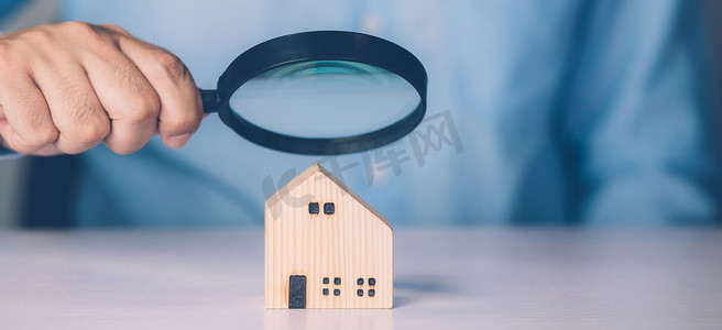 品质检查摄影照片_商人的手拿着放大镜看房子，用于检查和分析质量、检查和检查房屋、购买和搜索住宅和投资、商业和房地产概念。