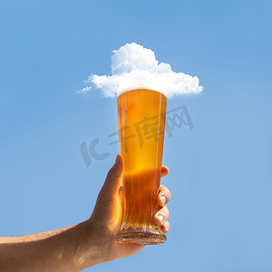 云鱼摄影照片_男人拿着啤酒杯，上面有云