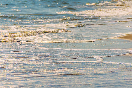 海水的特写影响沙滩上的沙子，海浪平静地流沙，放松的景色