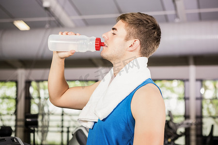 喝水的男人摄影照片_在健身房跑步机上喝水的人