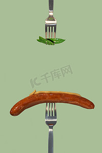 用叉子采摘的绿色鲜叶作为新的素食食品和烤香肠，在另一把叉子上放上芥末酱，色拉色纯色背景，有文字、特写、细节的复制空间