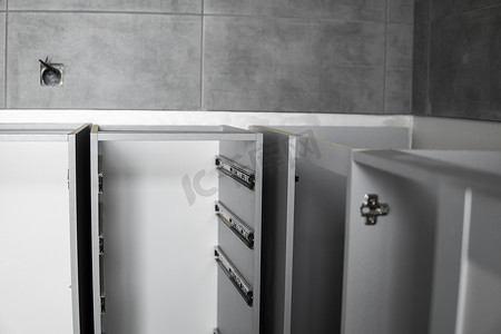 不锈钢伸缩卡口式抽屉滑轨，安装在灰色刨花板制成的厨柜上。