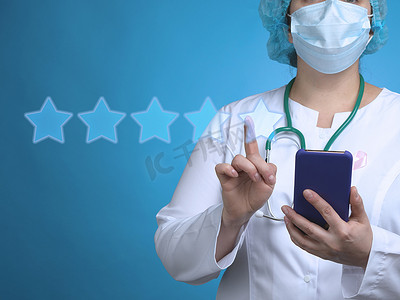 一位女医生站在蓝色背景上，手持智能手机，另一只手点击虚拟评级星