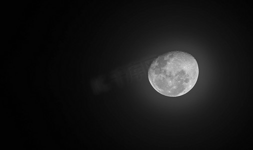 通过望远镜看到的月球，有可见的陨石坑和宁静的大海。