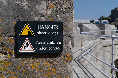 危险突然坠落标志黄色警示三角形，标志为男子从悬崖边缘坠落并控制儿童