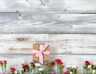 五颜六色的康乃馨花和礼物在 whi 上形成底部边框