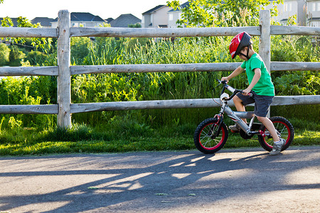 骑自行的男孩摄影照片_在公园的自行车道上骑自行车的儿童