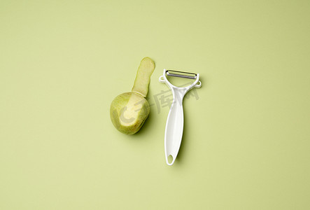 削水果摄影照片_绿色背景中用于剥蔬菜水果和青苹果的塑料刀