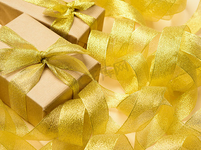 在扭曲的金丝带背景、节日背景、顶视图上用棕色纸包裹的礼物