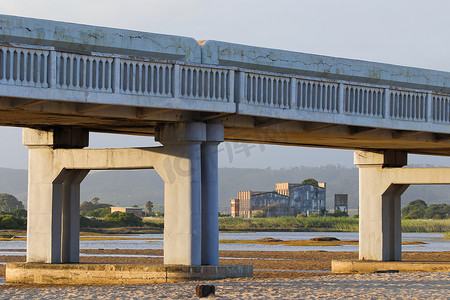 废弃工厂摄影照片_横跨沙洲与废弃工厂的桥梁