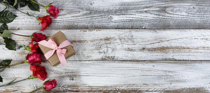 母亲节或情人节假期，质朴木板左侧的真红花圈和礼盒