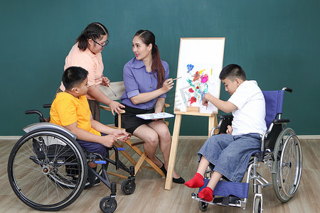 自闭症日宣传摄影照片_亚裔残障儿童或自闭症儿童正在用水作画训练手部和手指的肌肉。