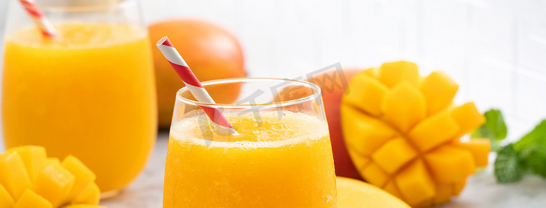 灰色桌子背景上的玻璃杯中的新鲜芒果汁冰沙。