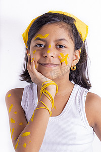 儿童脸上摄影照片_快乐的小女孩，脸上涂着彩绘来庆祝黄色的日子