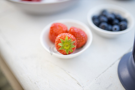 白草莓摄影照片_白桌上小盘子里的草莓