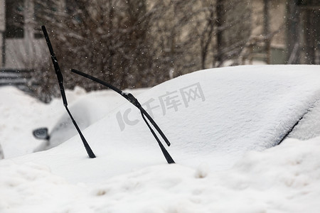 雨刷在阴天光下从积雪覆盖的汽车中伸出