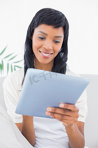 穿着白色衣服的体贴的黑发女人使用平板电脑