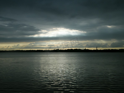日落时分，美丽的阳光透过乌云洞照亮湖水地平线。