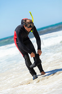 沙滩上带潜水服浮潜面罩脚蹼的男潜水员