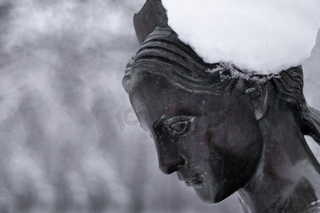 一个女人在冬季雪地公园的青铜纪念碑。