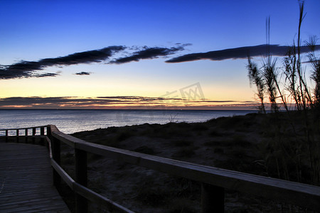 日出时通往西班牙阿利坎特海滩的木制人行道