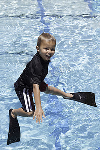 男孩用脚蹼从跳水板上跳下