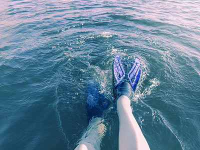 在炎热的夏日，脚蹼的腿在阳光下落入蓝色的水中