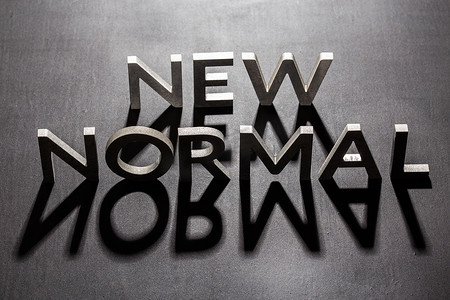 新的普通字由银色金属字母组成，在平坦的亚光黑色表面上带有阴影背光