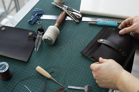 男士手在他的工作室里制作皮革钱包。