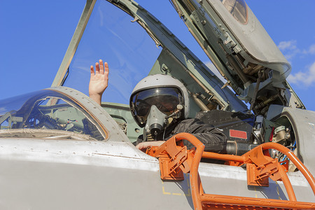 军事机场摄影照片_驾驶舱喷气式飞机的军事飞行员举起手