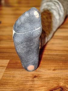 脏袜子摄影照片_破旧的袜子有洞，脚趾伸出来