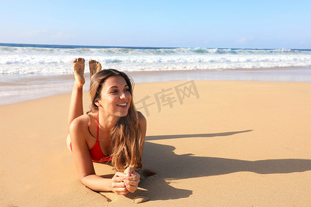 巴西微笑的美丽女孩躺在沙滩上晒日光浴，在暑假的加那利岛热带海滩放松，享受日光浴，看着旁边的复制空间区域