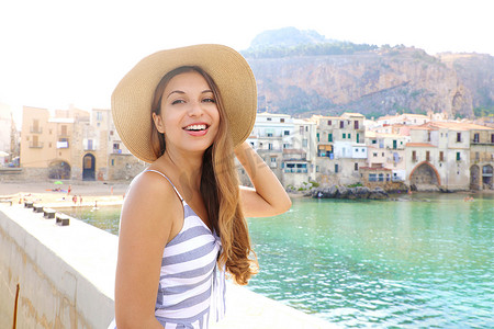 微笑的女人在西西里岛的暑假拿着草帽看着相机