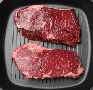 黑色方形烤盘中的两块生牛肉