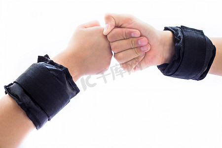 人类的一只手是一只男性，另一只女性的手被白色隔离，戴着黑色腕带或手腕重量被隔离在白色上。做各种手势以显示团结和力量。