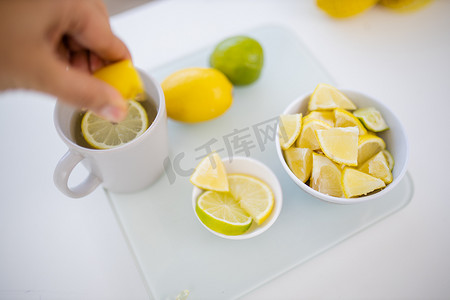女性手将柠檬挤入一杯柠檬茶中