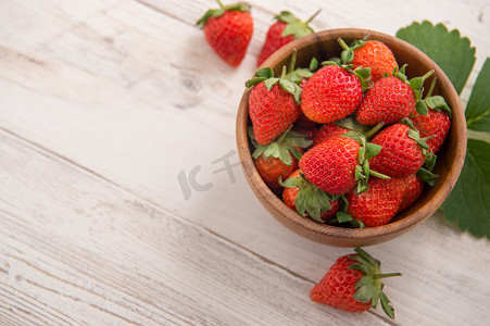 一碗美丽可口的草莓，隔离在浅色木质背景、特写、顶视图、复制空间中。