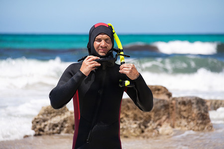 脚蹼摄影照片_沙滩上带潜水服浮潜面罩脚蹼的男潜水员