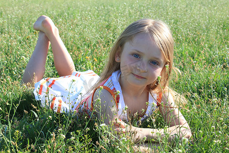 草地玩的孩子摄影照片_躺在草地上的小女孩肖像