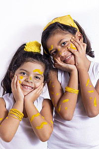 儿童脸上摄影照片_两个小女孩，脸上涂着彩绘来庆祝黄色的日子