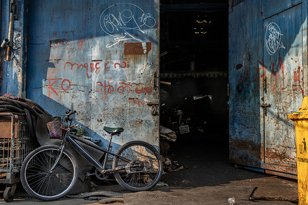 倾斜在老蓝色仓库门前面的老自行车。