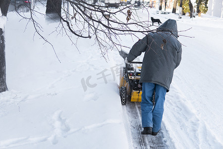 暴风雪过后，男子用造雪机清理车道。