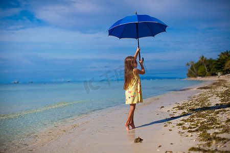 撑着雨伞摄影照片_白色沙滩上脚趾撑着雨伞的小女孩