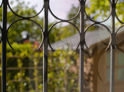 古代花园背景摄影照片_从带格栅的窗户看到的庭院和花园