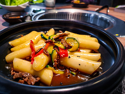 朝鲜民族摄影照片_一家韩国民族餐厅的韩国 Tteokbokki 饺子黑菜，配有甜 ganjang 酱油肉和西葫芦甜椒蔬菜