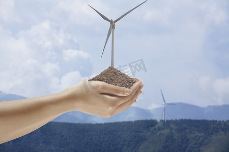 可持续资源摄影照片_手握土壤，中间长出风力涡轮机